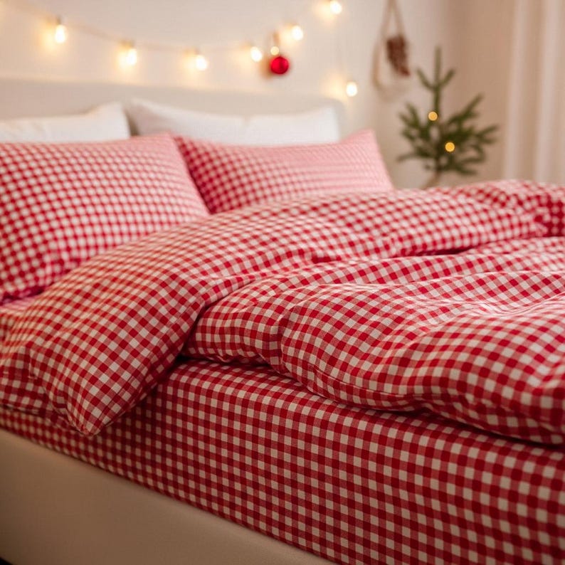 May include: A bed with red and white gingham bedding. The set includes a fitted sheet, a duvet cover, and two pillowcases. The room is decorated with string lights and a small Christmas tree.