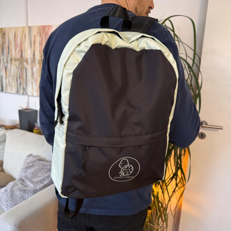 May include: Black and light green backpack with a turtle logo. The backpack has a large black front pocket and light green accents around the edges and straps. The turtle logo is in a white circle.