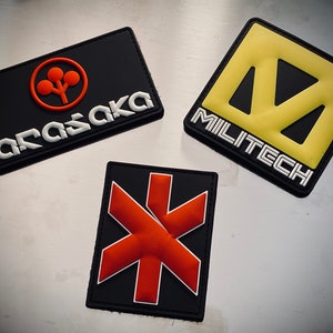 May include: Three rectangular patches with logos. One black patch has an orange logo and the word "ARASAKA" in white. Another has a yellow logo and the word "MILITECH" in white. The third has a red starburst design.