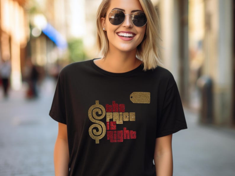 May include: A black short-sleeved t-shirt featuring a gold dollar sign and the text "the PRICE is right" in a mix of gold and red glittery lettering. A small gold rectangular price tag graphic is positioned above the text on the chest.