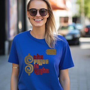 May include: A royal blue short-sleeved t-shirt featuring a large gold glitter dollar sign and the text "the price is right" in red and gold glitter lettering. A small gold glitter rectangular tag icon is positioned above the text.
