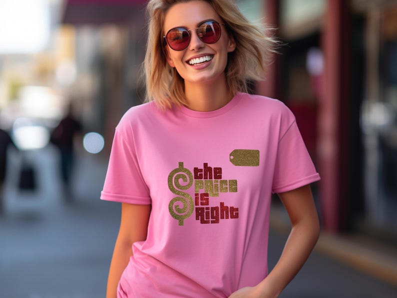 May include: A short-sleeved pink t-shirt featuring a gold glitter dollar sign, a gold glitter price tag icon, and the text "the PRICE is Right" in red and gold glitter lettering printed on the front of the garment.