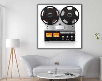 May include: A silver and black reel-to-reel tape recorder featuring two large black supply and take-up reels at the top, a central metal bridge, and a lower control panel with two illuminated orange analog VU meters and various knobs.