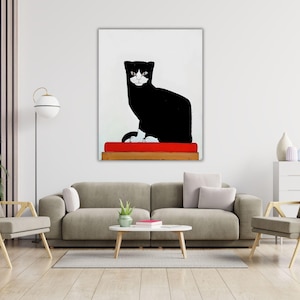 May include: A rectangular wall art print featuring a stylized black cat with white facial markings and white paws. The cat is sitting on a solid red rectangular cushion, which is placed on a brown wooden base against a plain white background.