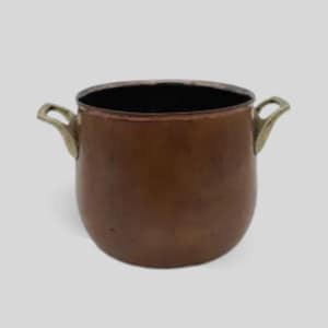 Puede incluir: Una olla de cobre con asas de latón. La olla tiene un cuerpo redondeado y un interior oscuro. Las asas son curvas y están unidas a los lados de la olla. Esta olla vintage es adecuada para cocinar o exhibir.