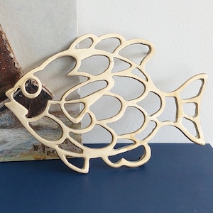 Pode incluir: Um descanso de panela de metal dourado em forma de peixe com um design recortado. O descanso de panela é feito de uma única peça de metal e tem um design detalhado e intrincado.