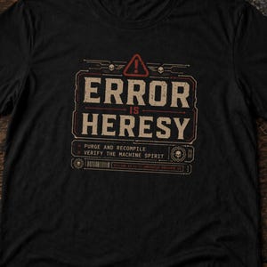 Peut inclure: T-shirt noir avec l'inscription "ERROR IS HERESY" dans un style vintage vieilli. Le design comprend un symbole d'avertissement et les phrases "PURGE AND RECOMPILE" et "VERIFY THE MACHINE SPIRIT".
