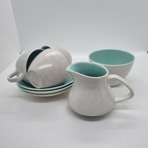 Könnte beinhalten: Ein Set vintage Teetassen und Untertassen mit weißer und hellblauer Glasur. Das Set enthält eine Kanne und eine Zuckerdose.