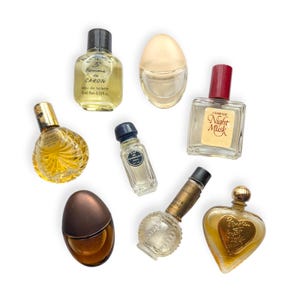 May include: A selection of vintage perfume bottles in diverse forms and dimensions. The bottles are transparent, amber, and brown, with gold and red highlights. Some bottles feature labels with text, including "Homme de Caron" and "Night Musk."