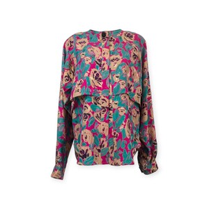 Op de afbeelding: Een blouse met lange mouwen en een bloemenpatroon in roze, teal en beige tinten. De blouse heeft een ronde hals en een knoopsluiting aan de voorkant. Het bloemmotief wordt over het hele kledingstuk herhaald.