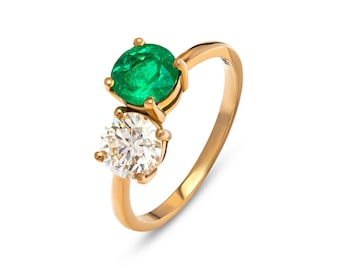 Könnte beinhalten: Ein goldener Ring mit einem großen Smaragd und einem kleineren runden Diamanten.