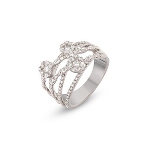 K&ouml;nnte beinhalten: Ein silberner Ring mit mehrschichtigem Design. Der Ring verf&uuml;gt &uuml;ber mehrere B&auml;nder, die mit kleinen, funkelnden Diamanten verziert sind. Das Design umfasst bl&uuml;tenartige Diamantencluster, die ein luxuri&ouml;ses und elegantes Aussehen erzeugen. Der Ring ist vor wei&szlig;em Hintergrund.