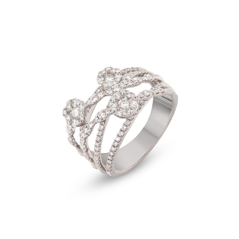 K&ouml;nnte beinhalten: Ein silberner Ring mit mehrschichtigem Design. Der Ring verf&uuml;gt &uuml;ber mehrere B&auml;nder, die mit kleinen, funkelnden Diamanten verziert sind. Das Design umfasst bl&uuml;tenartige Diamantencluster, die ein luxuri&ouml;ses und elegantes Aussehen erzeugen. Der Ring ist vor wei&szlig;em Hintergrund.