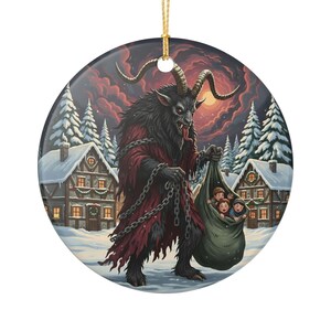 May include: A round ceramic ornament featuring a dark, horned creature with fur and a red robe, holding heavy metal chains and a large sack containing three children. The scene is set in a snowy village with pine trees under a dark, cloudy sky.
