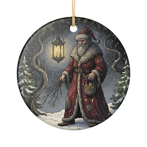 May include: A round ceramic ornament featuring a bearded figure in a long red fur-trimmed coat and hat, holding a bundle of twigs and a small pouch. The figure stands in a snowy forest at night, illuminated by a hanging lantern with a glowing candle.