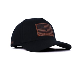 May include: Black baseball cap with a brown leather patch featuring an American flag design and a longhorn silhouette. The patch is rectangular and has the text "LONESTAR HERITAGE OUTFITTERS". The cap has a curved brim and a structured crown.