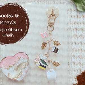 May include: A gold-toned Kindle charm chain with book, coffee cup, and leaf charms. The chain includes a pink heart-shaped charm and a brown circle with the text "Books & Brews Kindle Charm Chain".
