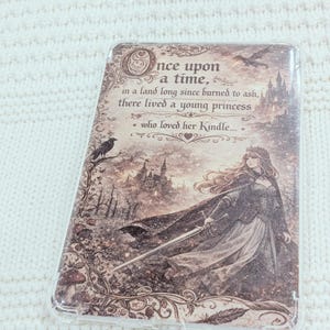 May include: A decorative Kindle cover with a princess illustration and castle backdrop. The cover features the text "Once upon a time... in a land long since burned to ash, there lived a young princess who loved her Kindle..."