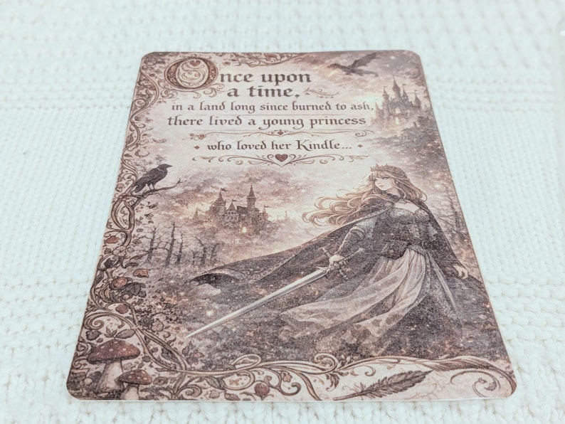 May include: A decorative card with a fantasy illustration. The card features a princess holding a sword, a castle, and the text "Once upon a time... who loved her Kindle." The color palette is sepia tones.