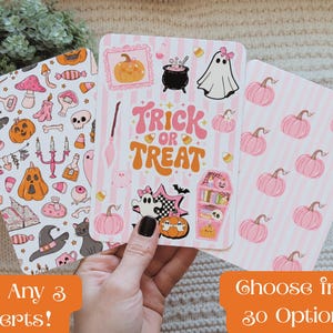 Puede incluir: Tres tarjetas rectangulares con ilustraciones temáticas de Halloween. La tarjeta de la izquierda tiene un patrón de calabazas, fantasmas y sombreros de bruja. La tarjeta central muestra el texto Trick or Treat con iconos de fantasmas y un ataúd. La tarjeta de la derecha tiene calabazas rosas.