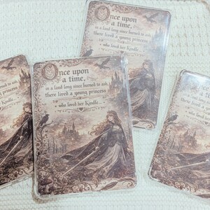 May include: Four rectangular phone cases with a fairytale design. Each case features the text "Once upon a time..." and an illustration of a princess, a castle, and crows in shades of brown and beige.