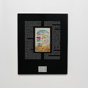 May include: A black and white image of a book cover with a colorful illustration of a city with a red car and a blue boat. The text on the cover reads "Le-100" and "Ecole". The back cover of the book has a barcode and text in French.