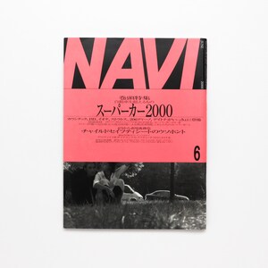 May include: A pink magazine cover with the title "NAVI" in black bold letters. The cover features the text "巻頭特集 自動車を超えるもの スーパーカー2000" in Japanese. The cover also features a black and white photo of two people sitting in a grassy field.
