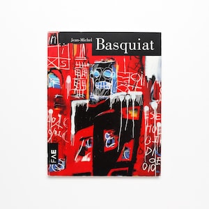 K&ouml;nnte beinhalten: Buchumschlag mit einem farbenfrohen abstrakten Gem&auml;lde von Jean-Michel Basquiat. Der Umschlag ist rot, schwarz, wei&szlig; und blau mit einer schwarzen Figur in der Mitte. Der Titel "Basquiat" steht in schwarzer Schrift oben auf dem Umschlag.