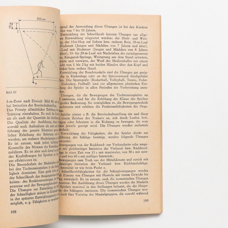 May include: A page from a German book with text and diagrams about sports training. The page includes text in German, diagrams, and measurements in centimeters. The book is open, showing the text and illustrations.