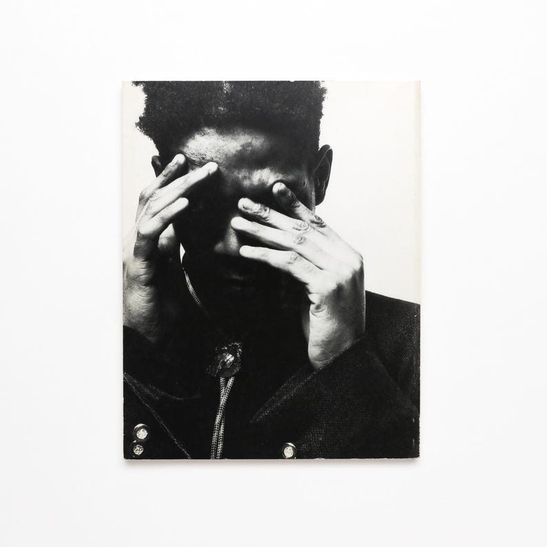 K&ouml;nnte beinhalten: Schwarzwei&szlig;foto einer Person, die sich mit den H&auml;nden das Gesicht bedeckt. Die Person tr&auml;gt eine dunkle Jacke.