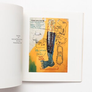 May include: Page from a book displaying a vibrant painting with text. The artwork features a human profile, a leg, and various symbols set against a yellow backdrop. Text includes phrases such as "STAFF INTO SERPENT TRICK" and "EGYPTIANS vs. MOSES."