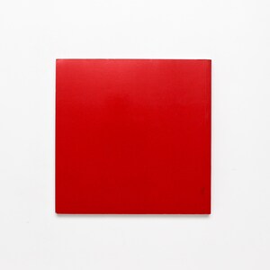 May include: A square of solid red against a white backdrop. The red is a vibrant, saturated hue, possibly with a glossy finish. The edges are clean and well-defined. The object is a square.
