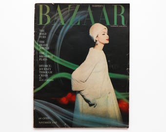 May include: Harper's Bazaar magazine cover from November 1958 featuring a woman wearing a white coat and hat against a black background with green and red streaks.