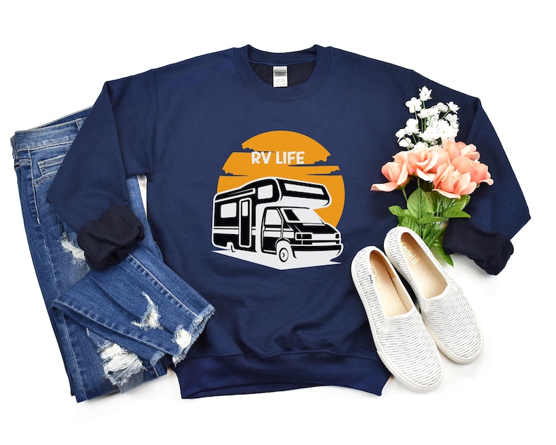 May include: A navy blue sweatshirt with the text "RV LIFE" printed on the front. The sweatshirt features a graphic of a camper van with a sunset behind it.