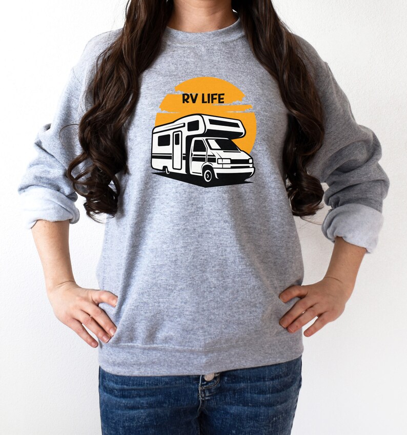 May include: A gray sweatshirt with a graphic of a camper van in front of a yellow sun with the text "RV LIFE" on it.