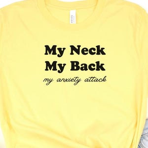 May include: Yellow t-shirt with black text that reads "My Neck My Back my anxiety attack"