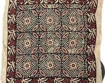 May include: A square fabric textile with a repeating pattern of brown and white floral designs. The fabric has a brown border with a floral design.