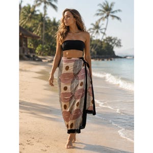 May include: A black strapless bandeau top paired with a long, lightweight sarong featuring a repeating geometric pattern of tan, brown, and muted red circles and ovals, finished with a solid black border along the side and hemline.