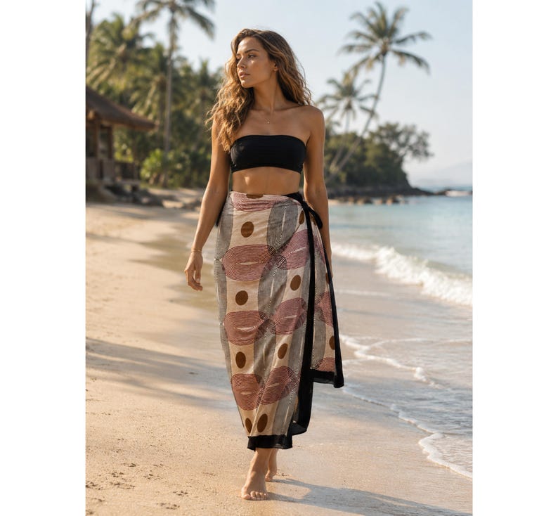 May include: A black strapless bandeau top paired with a long, lightweight sarong featuring a repeating geometric pattern of tan, brown, and muted red circles and ovals, finished with a solid black border along the side and hemline.