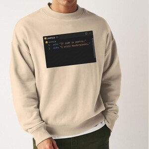 Könnte beinhalten: Beiges Sweatshirt mit schwarzer Grafik eines Code-Editor-Fensters. Der Text im Fenster lautet "If code is poetry," und "I write masterpieces." Das Sweatshirt hat einen lässigen Stil.