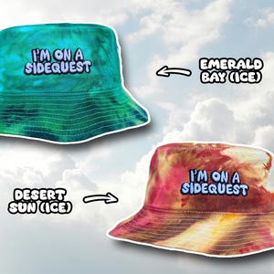 May include: Two tie-dye bucket hats with the text "I'm on a Sidequest" embroidered on the front. The hat on the left is green and blue, and the hat on the right is red and yellow. The text "Emerald Bay (Ice)" is above the left hat, and the text "Desert Sun (Ice)" is below the right hat.