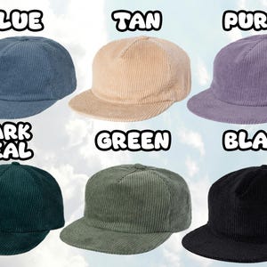 May include: Six corduroy baseball caps in various colors: blue, tan, purple, dark teal, green, and black. Each cap has a flat brim and a structured crown. The word for each color is written above each cap.