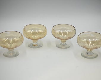 May include: Set of four amber glass dessert bowls with clear glass stems. The bowls are round and have a slight lip. The stems are short and have a round base.
