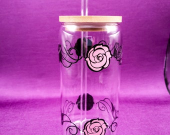 May include: A clear glass water bottle with a bamboo lid and a black and pink floral design. The bottle has a straw.