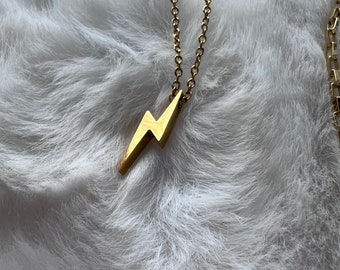 May include: A gold chain necklace with a lightning bolt pendant.
