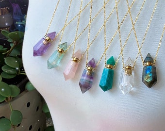 May include: A set of eight gold chain necklaces with crystal bottle pendants. The crystals are amethyst, aquamarine, rose quartz, fluorite, aventurine, clear quartz, and labradorite.