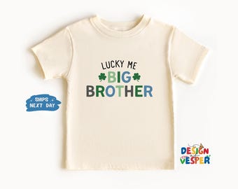 以下が含まれることがあります： クリーム色のTシャツに、「Lucky Me Big Brother」という文字が緑、青、グレーで書かれており、