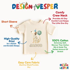 May include: Cream-colored short-sleeved t-shirt with a graphic of a Dalmatian dog wearing a party hat and holding a number 3 balloon. The name "JACOB" is printed below the dog. The shirt is made of 100% cotton.