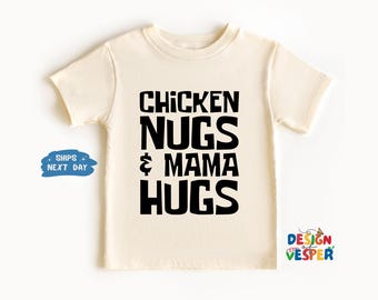 May include: A cream colored t-shirt with black text that reads "Chicken Nugs & Mama Hugs".