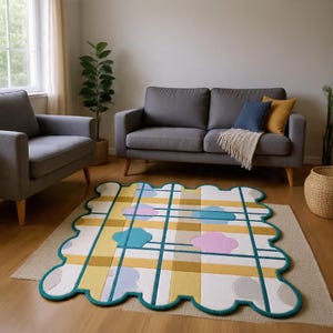 Op de afbeelding: Een kleurrijk vloerkleed met een geschulpte rand. Het vloerkleed heeft een rasterontwerp met gele, witte en blauwgroene accenten en wolkachtige ontwerpen in roze en blauw. Het vloerkleed ligt in een woonkamer.